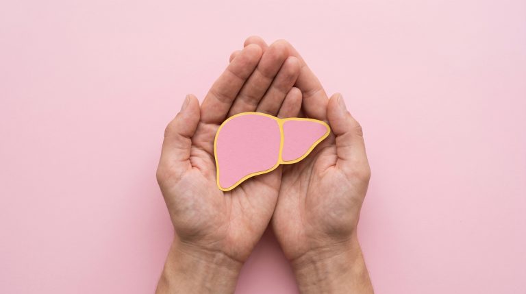 Mãos protegendo a ilustração de um fígado, representando a prevenção, os cuidados e a conscientização sobre as hepatites virais.