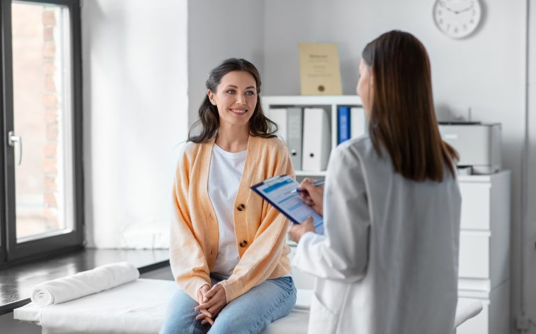 Mulher conversa com profissional de saúde durante consulta, representando o acompanhamento médico da doença falciforme.