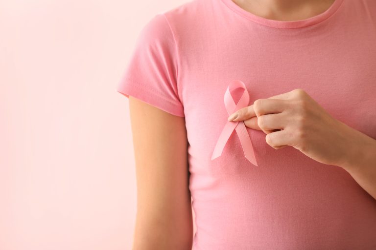 Mulher com laço rosa no peito, símbolo de conscientização e prevenção do câncer de mama.