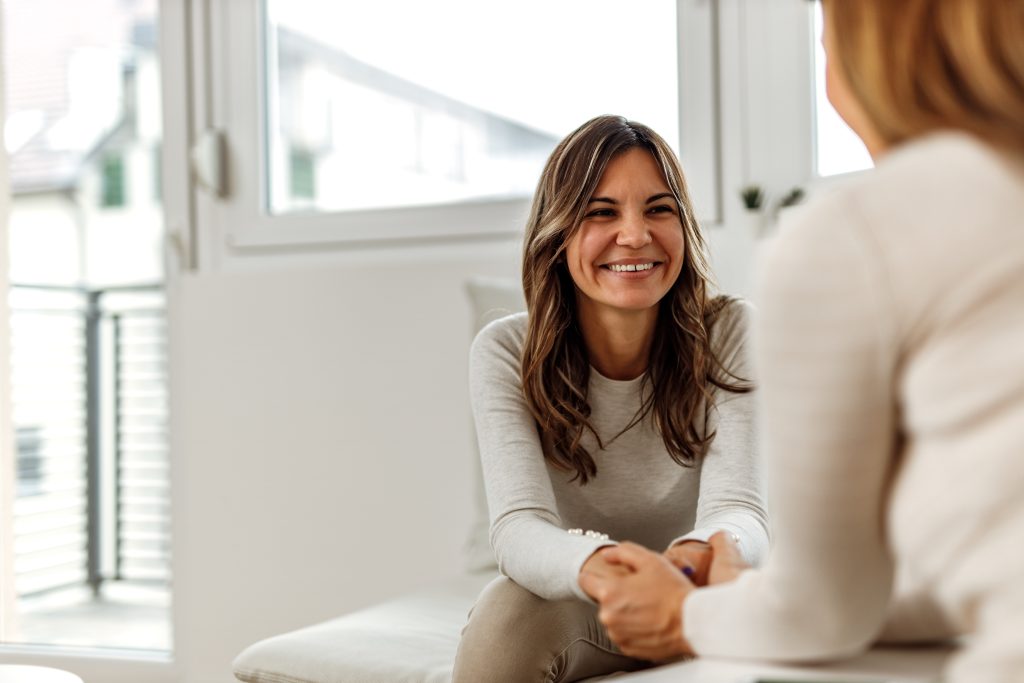 Mulher conversando com outra pessoa em ambiente acolhedor, representando diálogo, apoio e hábitos de cuidado com a saúde mental.